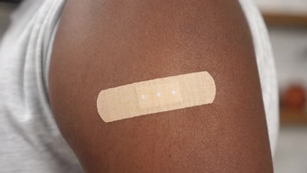 Acercarse hombre afroamericano vacunado con yeso médico en el hombro - Imágenes, Vídeo