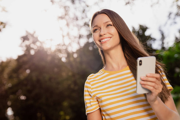 Photo portrait woman spending free time in summer park keeping smartphone smiling dreamy - Foto, Imagem