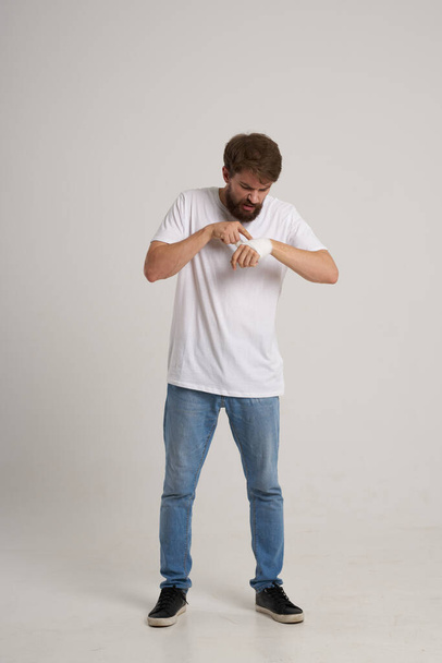 parrakas mies valkoisessa t-paidassa, jonka käsi on sidottu ja jonka tausta on eristetty - Valokuva, kuva
