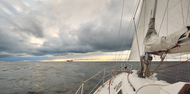 Bir kış günü açık denizde yat gezintisi. Güverteden pruvaya, direğe ve yelkenlere yakın görüntü. Dramatik fırtınalı gökyüzü, kara bulutlar. Destansı deniz manzarası. Kuzey denizi, Norveç - Fotoğraf, Görsel