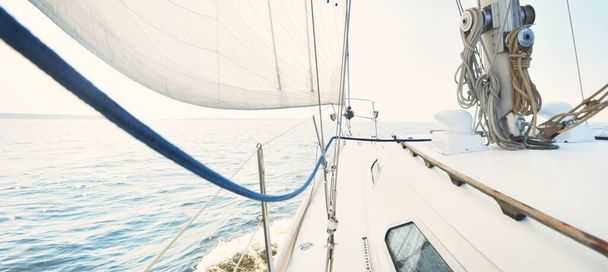 Witte jacht zeilen op een zonnige zomerdag. Close-up zicht van het dek naar de boeg en zeilen. Golven en waterspatten. Heldere blauwe lucht. Oostzee, Zweden - Foto, afbeelding