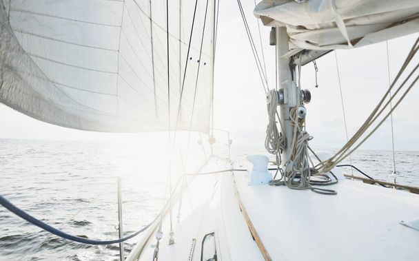 Weiße Jacht segelt an einem sonnigen Sommertag auf offener See. Nahsicht vom Deck auf Bug und Segel. Wellen und Wasser plätschern. Klarer blauer Himmel mit Zirruswolken und Flugbahnen. Niederlande - Foto, Bild