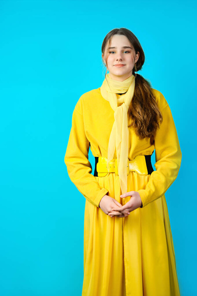 portrait of a teenage girl in yellow clothes. blue background - Фото, зображення