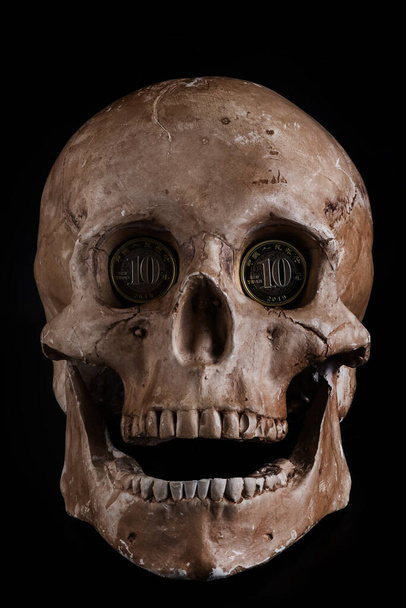 Egy emberi koponya bábuja 10 RMB érmével a szemüregében. - Fotó, kép