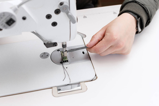 un hombre repara una máquina de coser de cerca con un destornillador - Foto, imagen