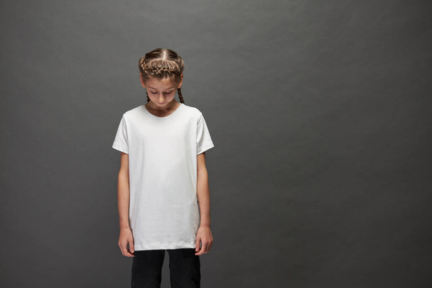 Kid lány visel fehér póló helyet a logó vagy design stúdióban szürke háttér - Fotó, kép