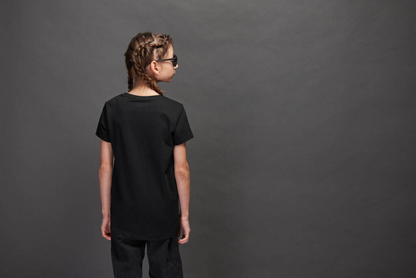 Kid girl wearing black t-shirt with space for your logo or design in studio over gray background - Foto, imagen