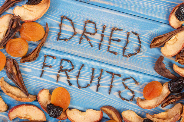 Inscription dried fruits and frame of ingredients for preparing beverage or compote of fruits on wooden boards, healthy nutrition - Foto, afbeelding