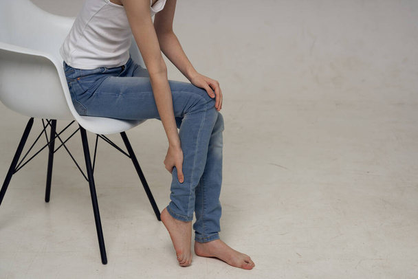 жінка сидить на стільці і нозі біль в суглобах проблеми зі здоров'ям
 - Фото, зображення