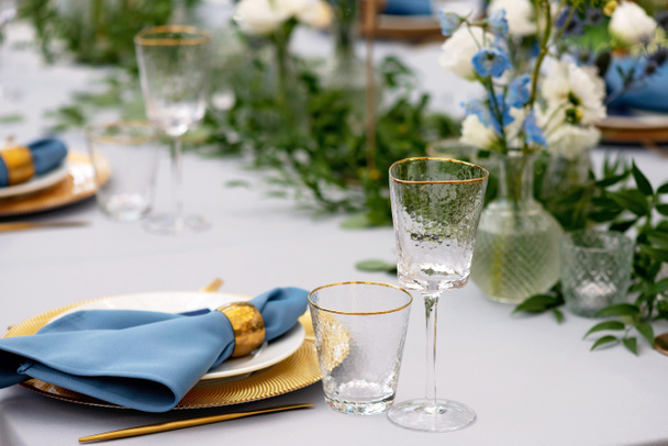 Elegante und schicke Tischdekoration in Gold- und Blautönen und frischen Blumen. Weiche selektive Fokussierung. - Foto, Bild