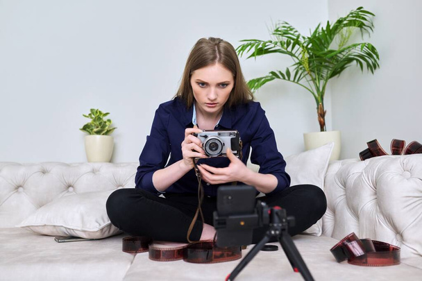Young woman photographer with vintage camera recording video on smartphone - Foto, afbeelding