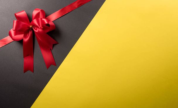 Top view of red ribbon decoration on black and yellow background. Shopping concept boxing day and Black Friday composition. - Foto, Imagem