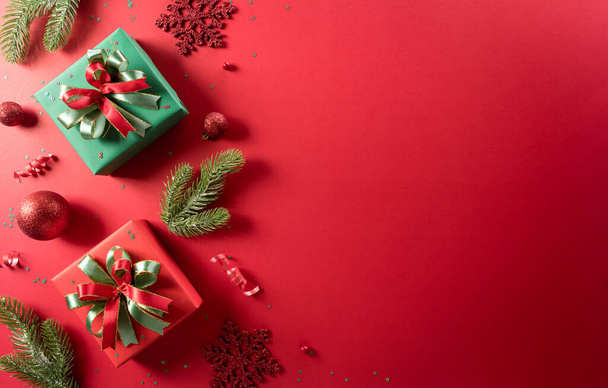 Noël et nouvelle année concept de fond. Vue du dessus de la décoration de Noël en boîte cadeau, flocon de neige, boule de Noël et branches de pin sur fond rouge. - Photo, image