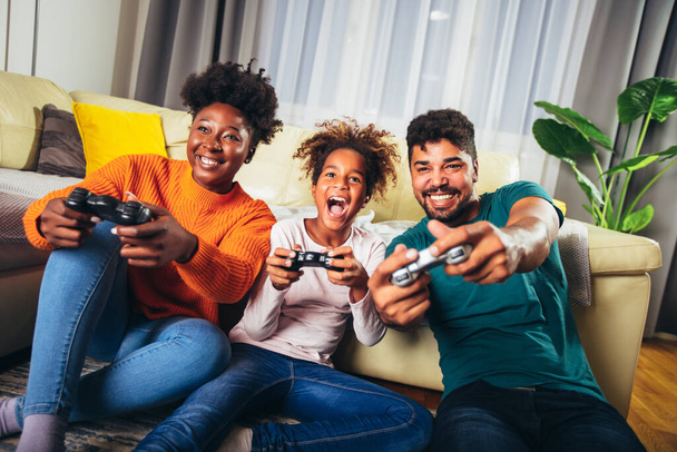 Afro-Amerikaanse familie spelen videospelletjes samen en plezier hebben thuis - Foto, afbeelding