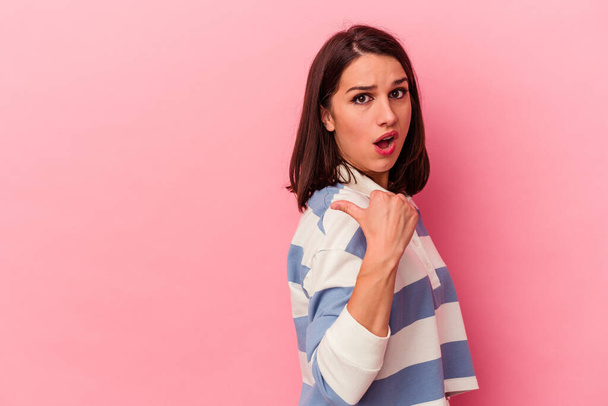 Young caucasian woman isolated on pink background points with thumb finger away, laughing and carefree. - Photo, image