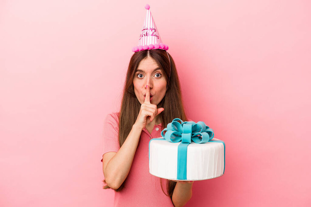 Young caucasian woman celebrating a birthday isolated on pink background keeping a secret or asking for silence. - Photo, Image