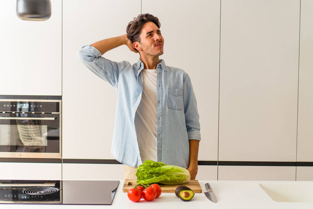 Fiatal vegyes fajú férfi készít egy salátát ebédre megható hátsó a fej, gondolkodás és a választás. - Fotó, kép