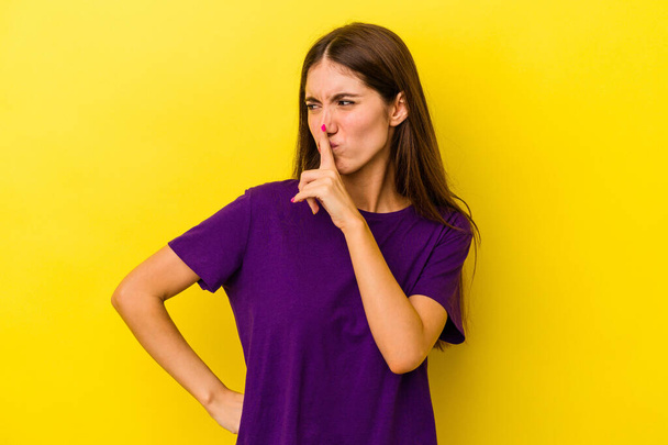 Young caucasian woman isolated on yellow background keeping a secret or asking for silence. - Foto, imagen