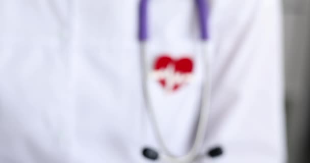 Κόκκινο εικονίδιο με τη μορφή ηλεκτροκαρδιογράφημα καρδιάς κρέμεται στο στήθος γιατρό closeup 4k ταινία - Πλάνα, βίντεο