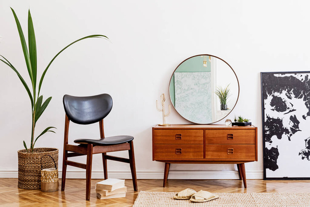 Minimalistic and stylish composition of living room with wooden commode, mirror, chair , lamp, tropical plant in rattan basket and elegant personal accessories. Interior design, Home decor. template - 写真・画像