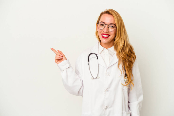 Kaukázusi orvos nő elszigetelt fehér háttér mosolygós és rámutatva félre, mutat valamit az üres térben. - Fotó, kép