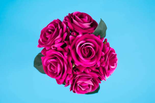 Bouquet of artificial roses on blue background - Foto, imagen