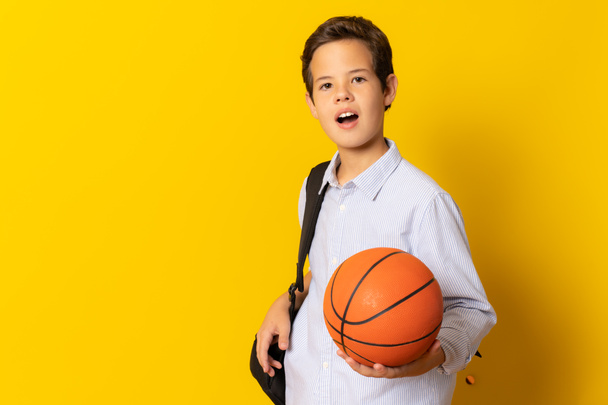 Schüler mit einem Basketball auf gelbem Hintergrund - Foto, Bild