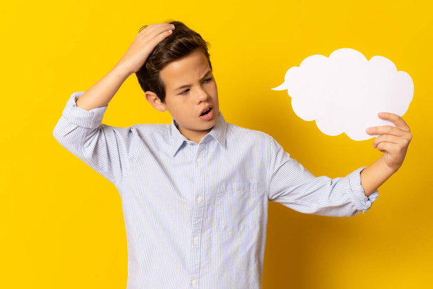 Great Idea. Amazed boy holding speech bubble with copy space standing isolated over yellow background. - Фото, изображение