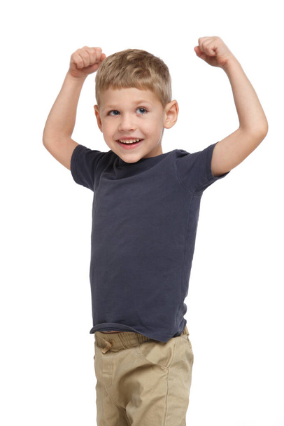 Little cute laughing boy in casual clothes shows how strong he is isolated on white background. - Фото, зображення