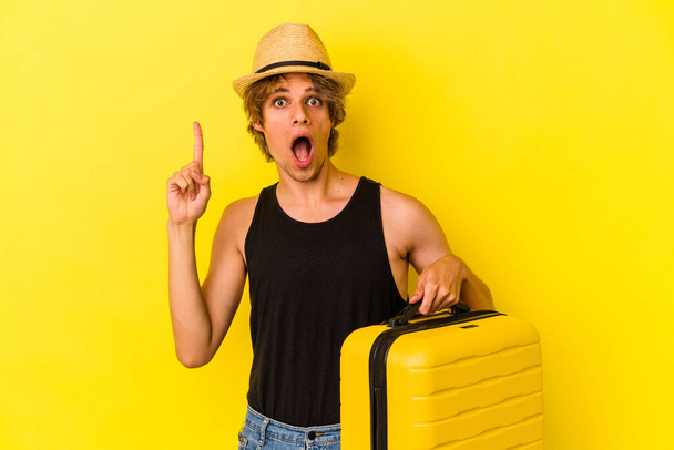 Giovane uomo caucasico con il trucco andando a viaggiare isolato su sfondo giallo avendo un'idea, concetto di ispirazione. - Foto, immagini