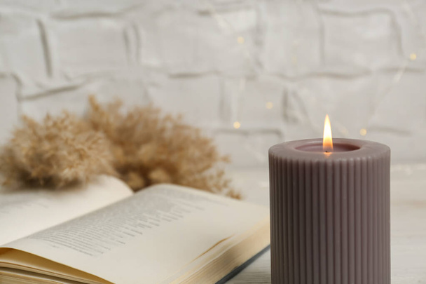 Burning candle and open book on table, space for text - Foto, Bild