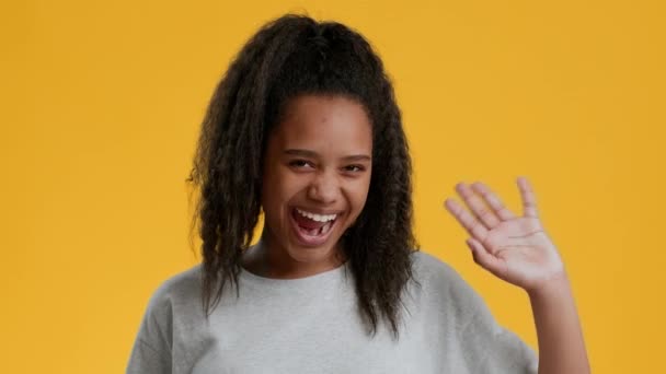 Vicces afro-amerikai tini lány integető kéz sárga háttér - Felvétel, videó
