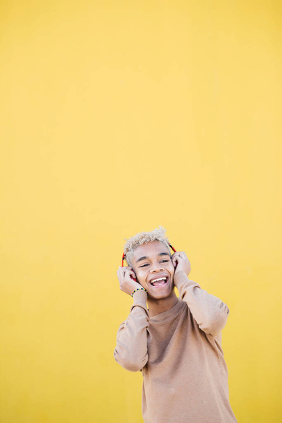 Portrait of Smiling Young man using red headphones and dancing Against yellow Background - Valokuva, kuva