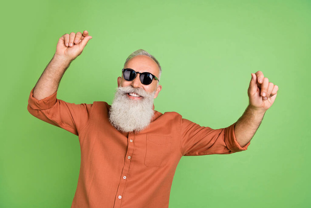 Portrait of attractive cheerful grey-haired man dancing having fun rest resort isolated over green color background - Fotoğraf, Görsel