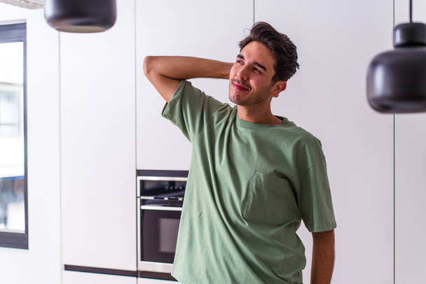 Молодий змішаний гоночний чоловік на своїй кухні торкається голови, думаючи і роблячи вибір
. - Фото, зображення
