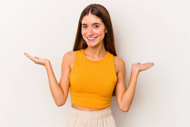 Young caucasian woman isolated on white background makes scale with arms, feels happy and confident. - Fotó, kép