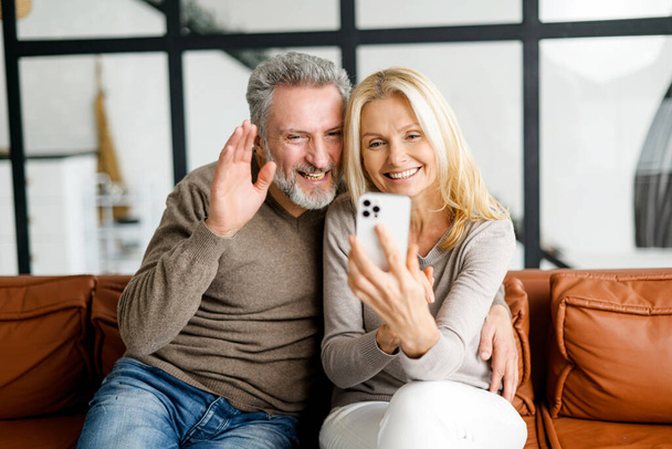 Middle-aged couple is taking selfie by a smartphone or making video call - Φωτογραφία, εικόνα