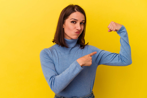 Young caucasian woman isolated on yellow background showing strength gesture with arms, symbol of feminine power - Photo, image