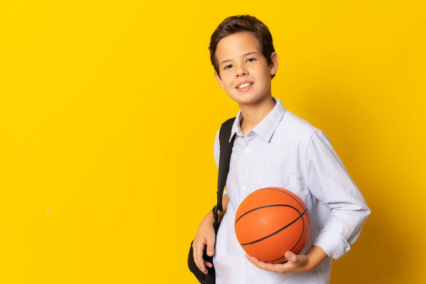 diák fiú egy kosárlabda elszigetelt sárga háttér - Fotó, kép
