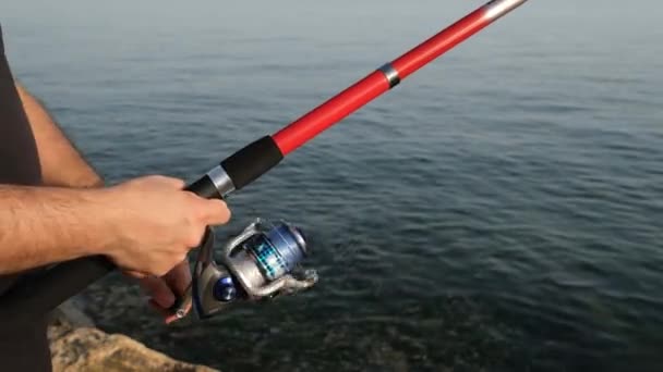vissen haspel, een man draait de visserij haspel door de zee - Video