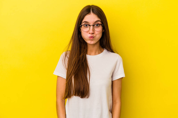 Young caucasian woman isolated on yellow background blows cheeks, has tired expression. Facial expression concept. - Fotografie, Obrázek