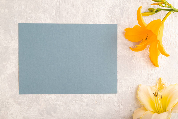 Tarjeta de visita de papel azul maqueta con flor de lirio de día naranja sobre fondo de hormigón gris. En blanco, vista superior, espacio para copiar, bodegón. concepto de primavera. - Foto, imagen