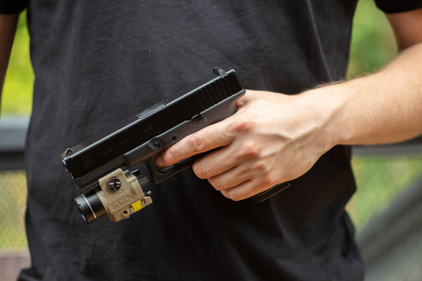 Male hand holding a black gun for playing airsoft. - Photo, image