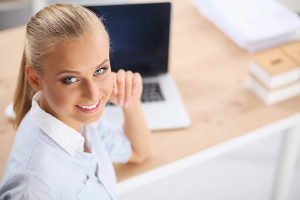 Attractive businesswoman sitting on a desk with laptop in the o - Photo, Image
