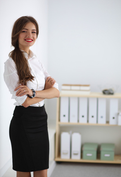 Attractive businesswoman with her arms crossed  standing in off - 写真・画像