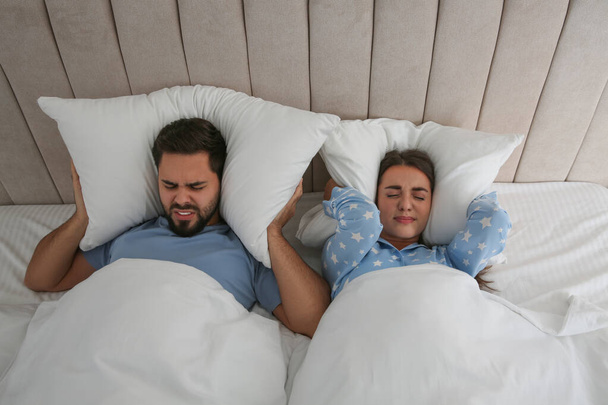 Young couple suffering from noisy neighbours in bed at home, above view - Foto, Bild