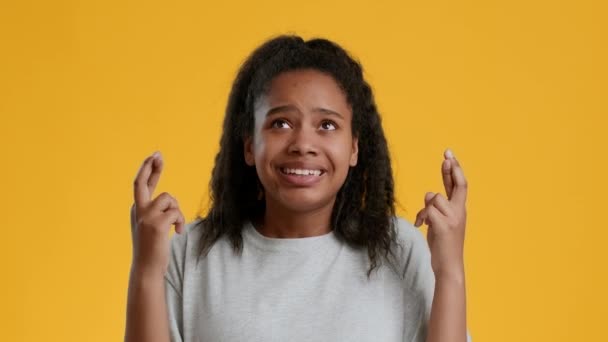 Angst zwart tiener meisje houden vingers gekruist over gele achtergrond - Video