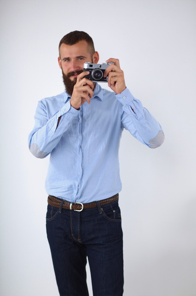 Young beard man focusing at you with his camera while standing - Фото, зображення