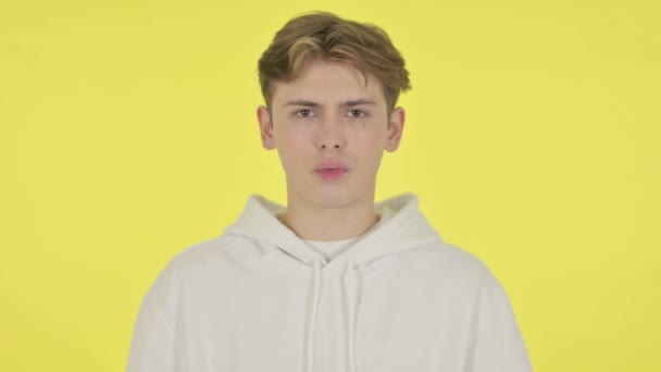 Fiatal férfi mutatja No Sign által Shaking Head sárga háttér  - Felvétel, videó