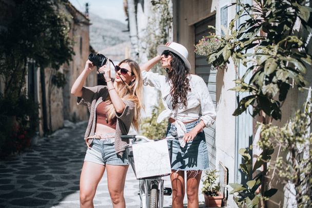 Turystyczne kobiety podróżują z kamerą i mapą. Koncepcja turystyki. Dwie dziewczyny w środę robią zdjęcia. - Zdjęcie, obraz